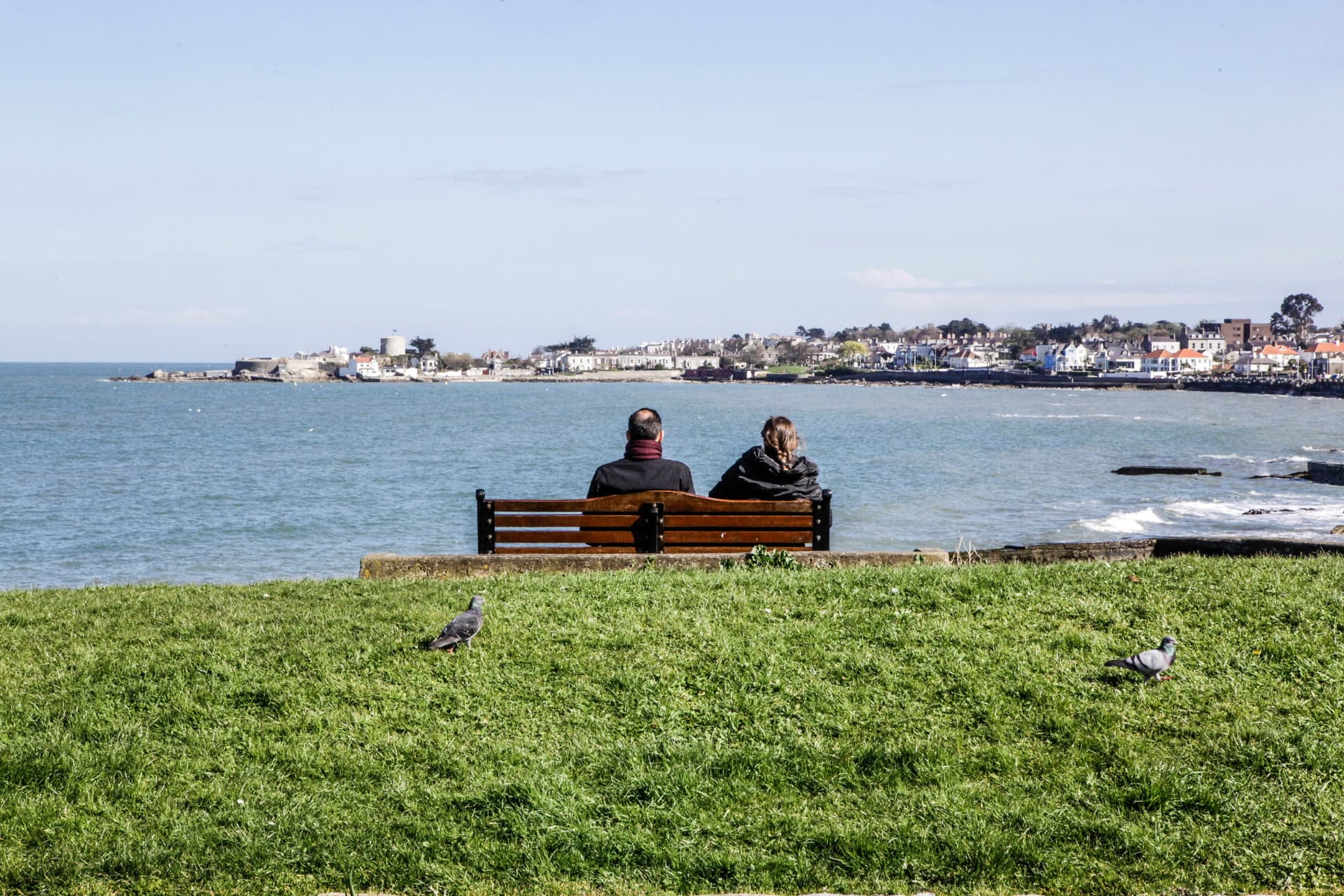 A couple sitting on a bench looking out over Dún Laoghaire Bay